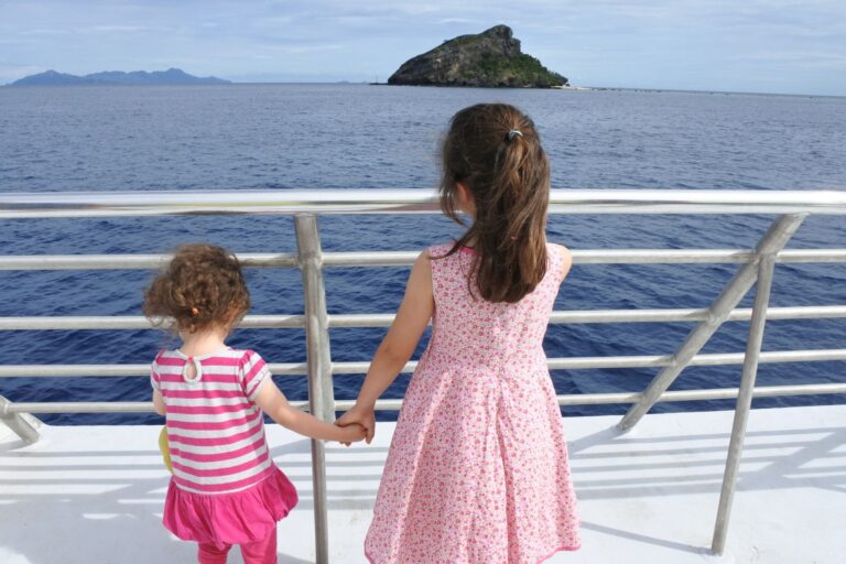 2 kids on a cruise looking through the railing
